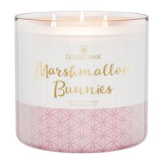 a white candle that says marshmallow bunnies in gold lettering on the front