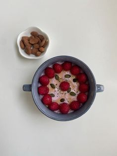 a bowl filled with raspberries and almonds on top of a white table