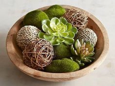 a wooden bowl filled with lots of green succulents on top of a table