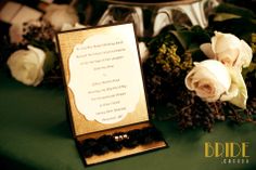 a table topped with white roses and black beads next to a wooden box filled with wedding rings