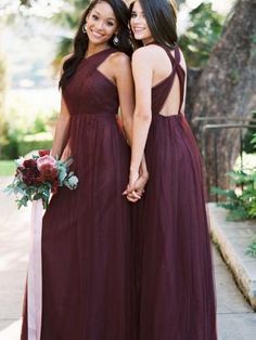 two women in long dresses standing next to each other with their arms around each other