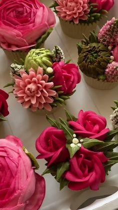 cupcakes decorated with pink and green flowers are on a white tray, ready to be eaten