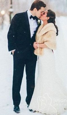 a bride and groom kissing in the snow