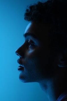 a woman's profile in the dark with blue light coming from behind her head