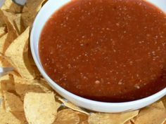 a white bowl filled with salsa surrounded by tortilla chips