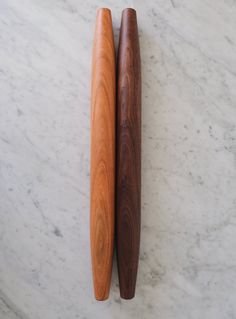 two wooden spoons sitting next to each other on a marble surface