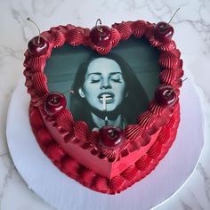 a heart shaped cake with cherries on the side and a photo of a woman sticking her tongue out