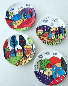 three small plates painted with houses and trees on them, all in different shapes and sizes