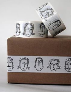 two rolls of tape with faces on them sitting on top of a cardboard box next to each other