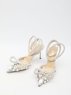 These high heels feature a transparent upper adorned with large stones and silver-tone crystals. The pointed toe is accented with a double crystal bow, while an adjustable ankle strap adds practicality. The leather insole and stiletto heel provide comfort and elegance, while the leather sole ensures durability. A dust bag and additional crystals and heels are also included. Heel height: 3.3 inches Size nationality: IT Product code: FW24-S081885X03B20 Composition: 100% pvc Silver Heels With Bow For Wedding, Glamorous Wedding Shoes With Bow For Evening, Silver Heels With Bow For Formal Occasions, Glamorous Silver Heels With Bow, Glamorous Wedding Shoes With Bow, High Heel Rhinestone Wedding Shoes For Cocktail, Rhinestone High Heel Wedding Shoes For Cocktail, Crystal High Heel Wedding Shoes For Evening, Silver Crystal Heels With Pointed Toe