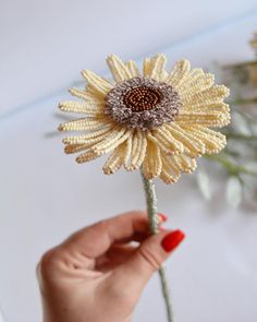 a woman holding a yellow flower in her hand