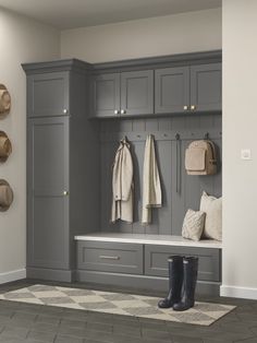 an entryway with gray cabinets and coat racks on the wall, along with boot boots