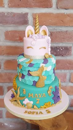 there is a multi layer cake with a unicorn on top and mermaid decorations around the edges