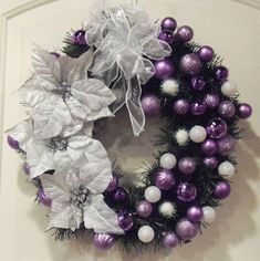 a purple and white christmas wreath hanging on the front door