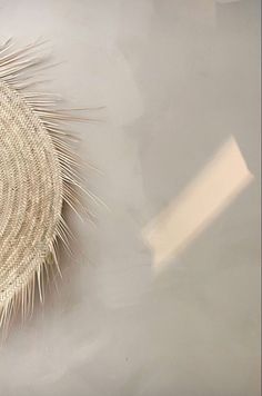 a close up of a woven object on a white tablecloth with a shadow from the floor