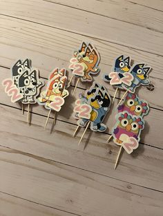 five cupcake toppers with cartoon characters on them sitting on a wooden table next to each other