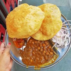 a person holding a plate with some food on it and two buns over the top