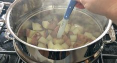 someone is stirring potatoes in a pot on the stove top with a blue spatula