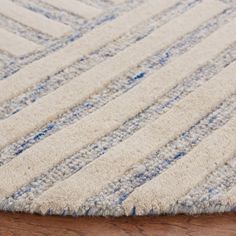 a close up of a rug on a wooden floor with blue and white stripes in the middle