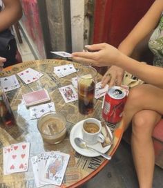 people sitting around a table with playing cards and drinks