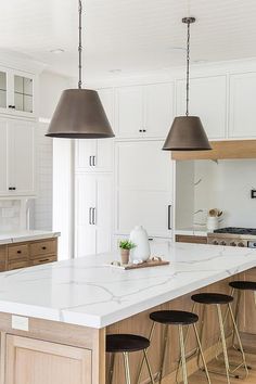 a large kitchen island with stools and lights hanging from it's ceiling over the counter