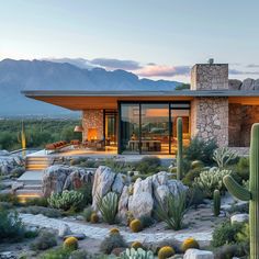 the desert house is surrounded by rocks and cacti, with mountains in the background