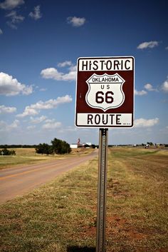 a route 66 sign on the side of a rural road in texas, with blue sky and clouds above it