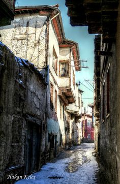 an alley way with snow on the ground and buildings in the backgrouds