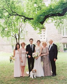 a group of people standing next to each other in front of a tree with a dog