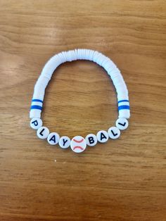 a white and blue beaded bracelet that says play ball on it with baseball balls