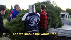 three men standing in front of a truck with trees on the back and one man holding a tree