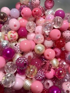 there are many different colored beads in the bowl on the table and one is pink