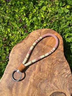 a wooden board with a rope on it and a metal ring hanging from the end