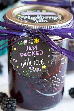 jam packed with love in a jar and tied with purple ribbon on the top, surrounded by blackberries