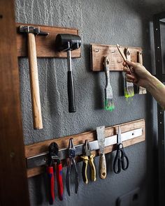 there is a man that is working on the wall with tools hanging from it's hooks