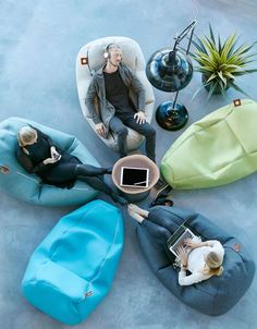 a man sitting in a bean bag chair surrounded by other furniture and accessories on the floor