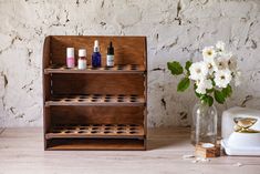 a wooden shelf with bottles on it next to a vase filled with flowers and other items