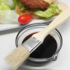 a white plate topped with lettuce and tomatoes next to a paint can filled with black liquid