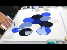 a person is using blue and black paint on a piece of paper with circles around it