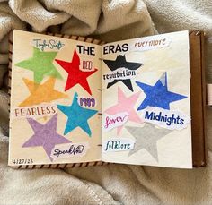 an open book with colorful stars on the pages and words written in different languages, sitting on a blanket