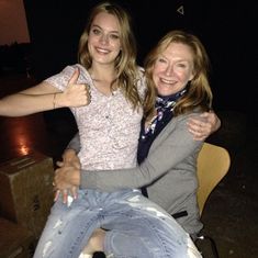 two women sitting on top of each other with their arms around one another and giving the thumbs up