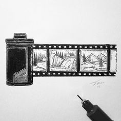 a hand holding a pen and drawing pictures on a white wall with film strips attached to it