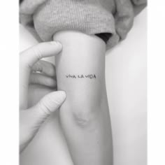 a woman's arm with the word va la landa tattooed on her left arm