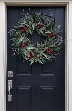 a wreath on the front door of a house with holly and red berries hanging from it