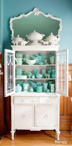 a white china cabinet filled with lots of dishes