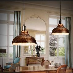 two pendant lights hanging over a dining room table