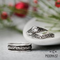 two wedding rings sitting next to each other on top of a white plate with flowers in the background