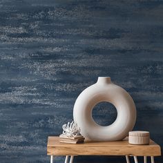 a white vase sitting on top of a wooden table