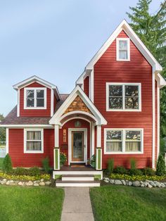 a red house with white trim and green shutters on the front door is shown