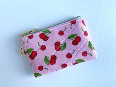 a pink purse with cherries on it sitting on top of a white table next to a blue wall